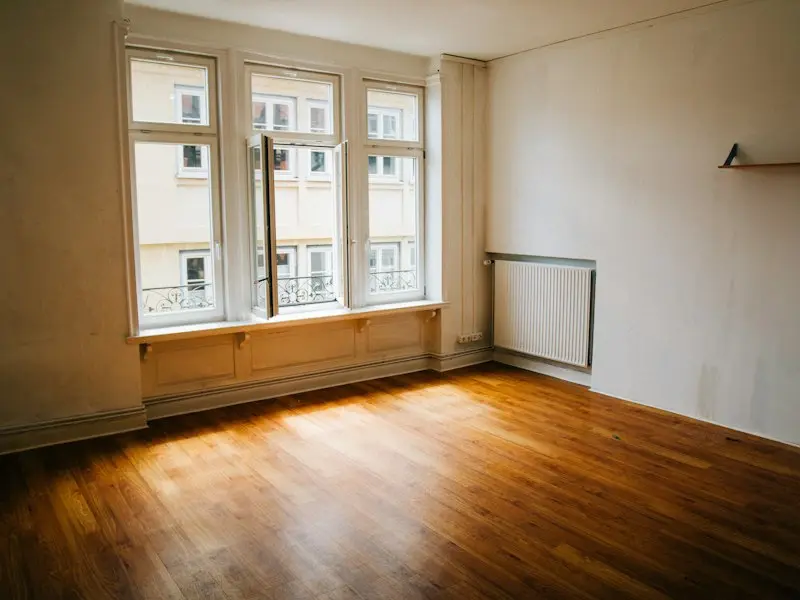 Leeres Zimmer mit Parkett und großen Fenstern