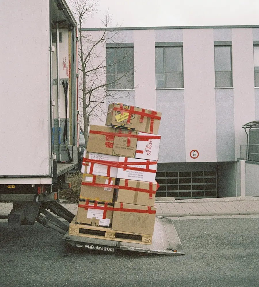 Umzugskartons auf einer Palette neben dem Umzugswagen